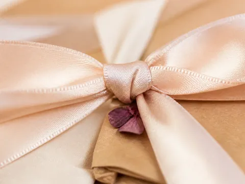 Kraft kâğıda sarılı paketin üstünde saten kurdele fiyonk ve kurutulmuş bir yaprak